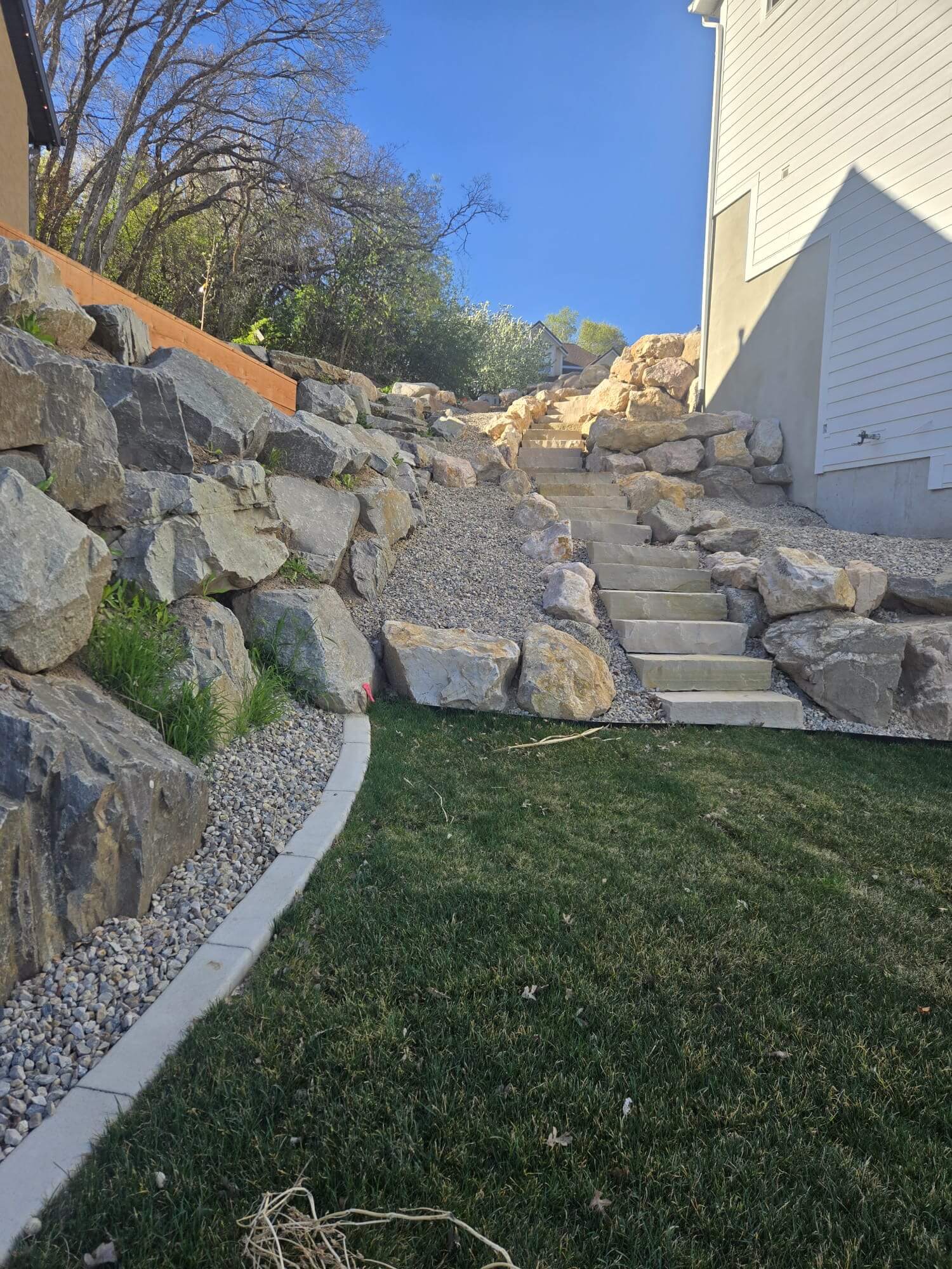 Terraced boulder walls with concrete steps between two homes